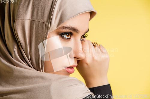 Image of Beautiful arab woman posing in stylish hijab isolated on yellow studio background. Fashion, beauty, style concept