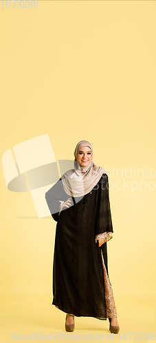 Image of Beautiful arab woman posing in stylish hijab isolated on yellow studio background. Fashion, beauty, style concept