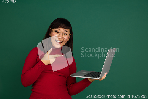 Image of East asian woman\'s portrait isolated on green studio background with copyspace