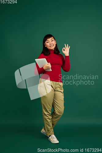 Image of East asian woman\'s portrait isolated on green studio background with copyspace