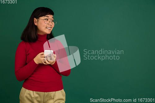 Image of East asian woman\'s portrait isolated on green studio background with copyspace