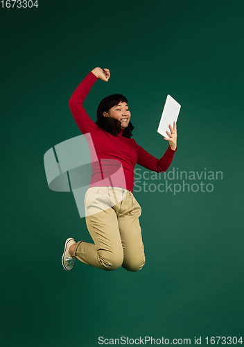 Image of East asian woman\'s portrait isolated on green studio background with copyspace