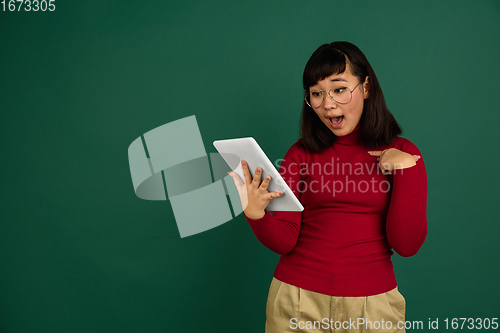 Image of East asian woman\'s portrait isolated on green studio background with copyspace