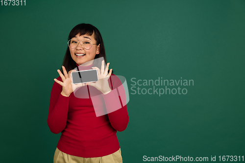 Image of East asian woman\'s portrait isolated on green studio background with copyspace