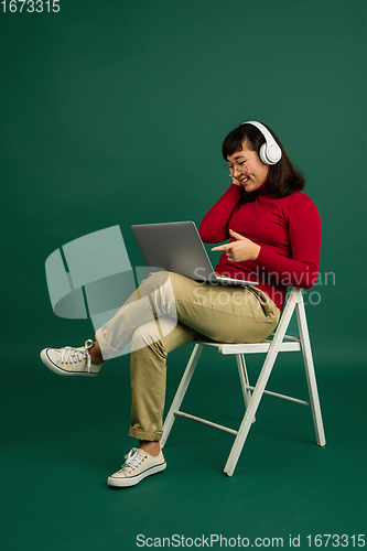 Image of East asian woman\'s portrait isolated on green studio background with copyspace