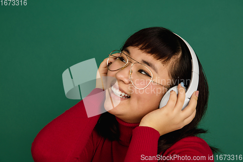 Image of East asian woman\'s portrait isolated on green studio background with copyspace