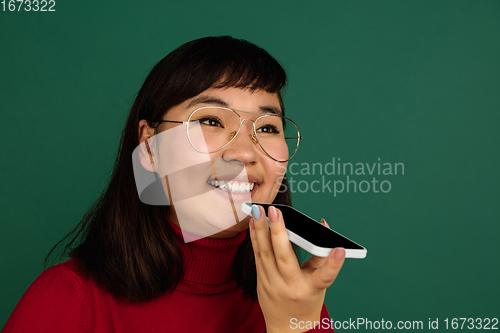 Image of East asian woman\'s portrait isolated on green studio background with copyspace