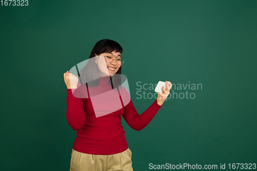 Image of East asian woman\'s portrait isolated on green studio background with copyspace