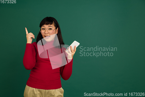 Image of East asian woman\'s portrait isolated on green studio background with copyspace