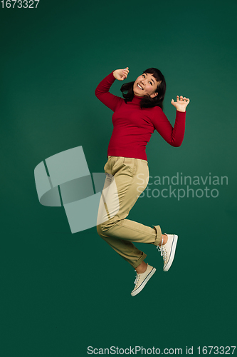 Image of East asian woman\'s portrait isolated on green studio background with copyspace