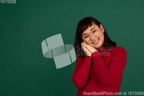 Image of East asian woman\'s portrait isolated on green studio background with copyspace