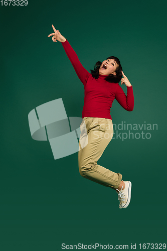 Image of East asian woman\'s portrait isolated on green studio background with copyspace