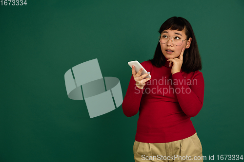 Image of East asian woman\'s portrait isolated on green studio background with copyspace