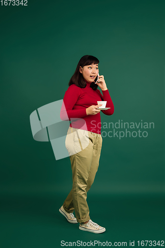 Image of East asian woman\'s portrait isolated on green studio background with copyspace