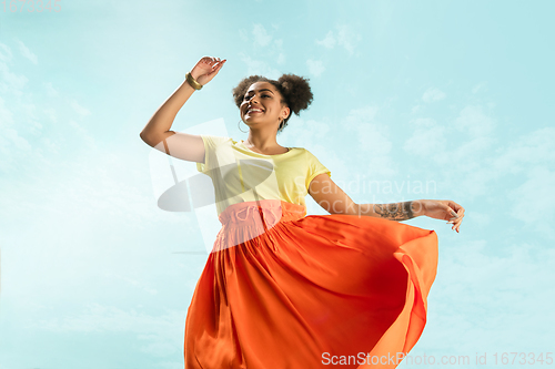 Image of Portrait of female fashion model on blue sky background. Style and beauty concept, bright appearance