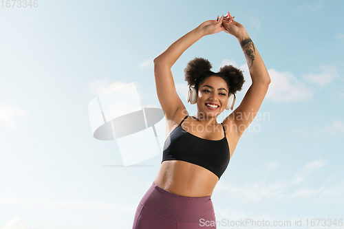 Image of Portrait of female fashion model on blue sky background. Style and beauty concept, bright appearance. Lifestyle sport.