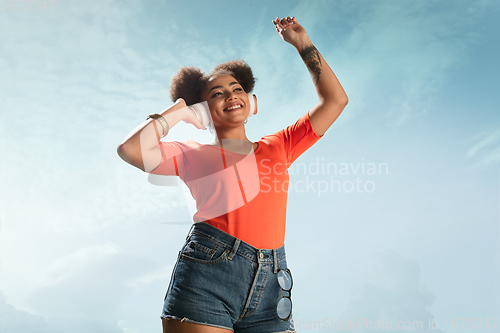 Image of Portrait of female fashion model on blue sky background. Style and beauty concept, bright appearance