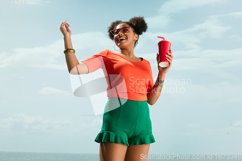 Image of Portrait of female fashion model on blue sky background. Style and beauty concept, bright appearance