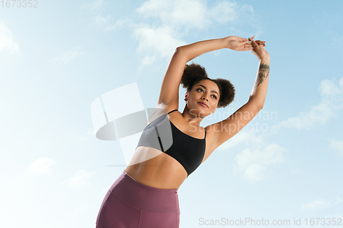 Image of Portrait of female fashion model on blue sky background. Style and beauty concept, bright appearance. Lifestyle sport.