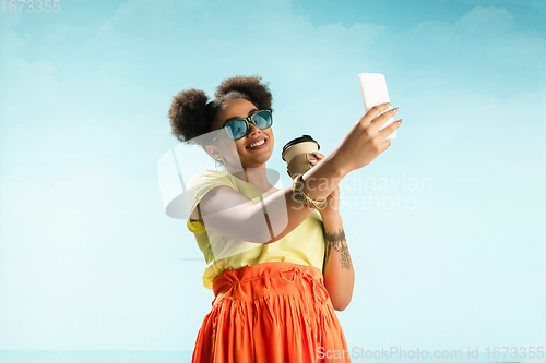 Image of Portrait of female fashion model on blue sky background. Style and beauty concept, bright appearance