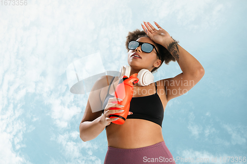 Image of Portrait of female fashion model on blue sky background. Style and beauty concept, bright appearance. Lifestyle sport.