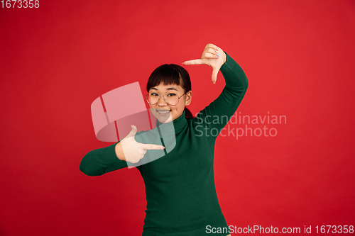 Image of East asian woman\'s portrait isolated on red studio background with copyspace