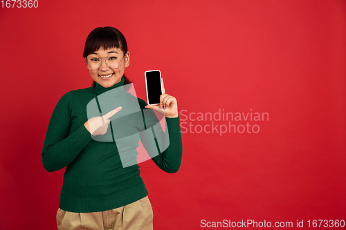 Image of East asian woman\'s portrait isolated on red studio background with copyspace