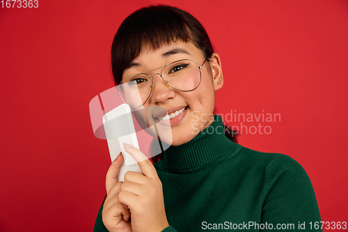 Image of East asian woman\'s portrait isolated on red studio background with copyspace