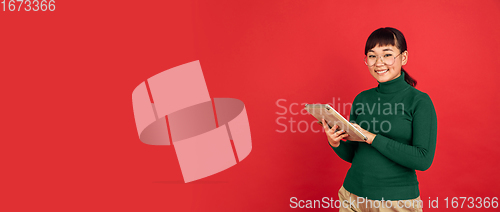 Image of East asian woman\'s portrait isolated on red studio background with copyspace