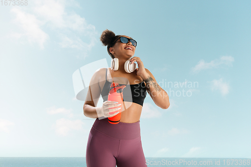 Image of Portrait of female fashion model on blue sky background. Style and beauty concept, bright appearance. Lifestyle sport.