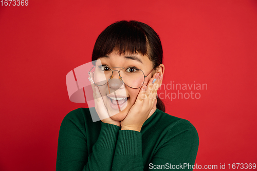 Image of East asian woman\'s portrait isolated on red studio background with copyspace