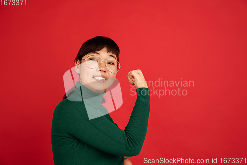 Image of East asian woman\'s portrait isolated on red studio background with copyspace