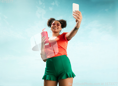 Image of Portrait of female fashion model on blue sky background. Style and beauty concept, bright appearance