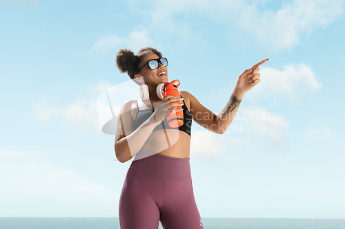 Image of Portrait of female fashion model on blue sky background. Style and beauty concept, bright appearance. Lifestyle sport.