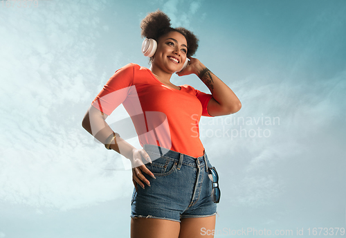 Image of Portrait of female fashion model on blue sky background. Style and beauty concept, bright appearance