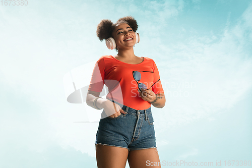 Image of Portrait of female fashion model on blue sky background. Style and beauty concept, bright appearance