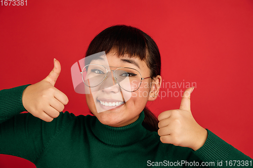 Image of East asian woman\'s portrait isolated on red studio background with copyspace