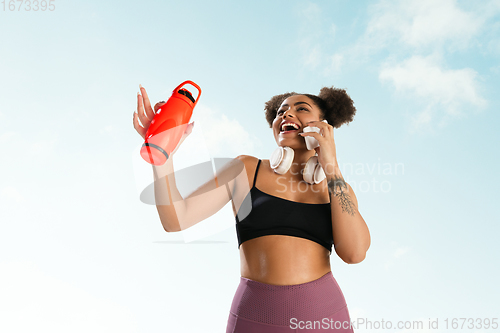 Image of Portrait of female fashion model on blue sky background. Style and beauty concept, bright appearance. Lifestyle sport.