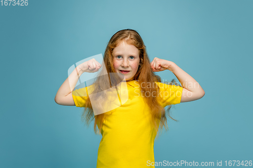 Image of Happy redhair girl isolated on blue studio background. Looks happy, cheerful, sincere. Copyspace. Childhood, education, emotions concept