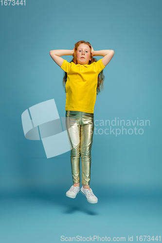 Image of Happy redhair girl isolated on blue studio background. Looks happy, cheerful, sincere. Copyspace. Childhood, education, emotions concept