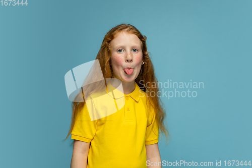 Image of Happy redhair girl isolated on blue studio background. Looks happy, cheerful, sincere. Copyspace. Childhood, education, emotions concept