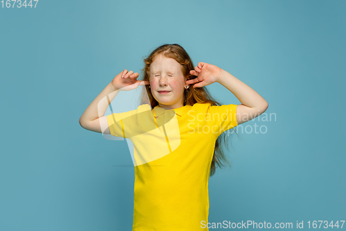 Image of Happy redhair girl isolated on blue studio background. Looks happy, cheerful, sincere. Copyspace. Childhood, education, emotions concept