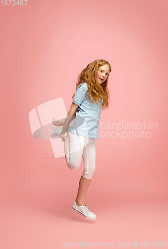 Image of Happy redhair girl isolated on pink studio background. Looks happy, cheerful, sincere. Copyspace. Childhood, education, emotions concept