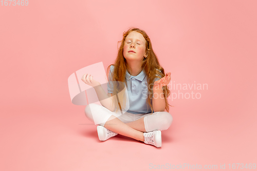 Image of Happy redhair girl isolated on pink studio background. Looks happy, cheerful, sincere. Copyspace. Childhood, education, emotions concept