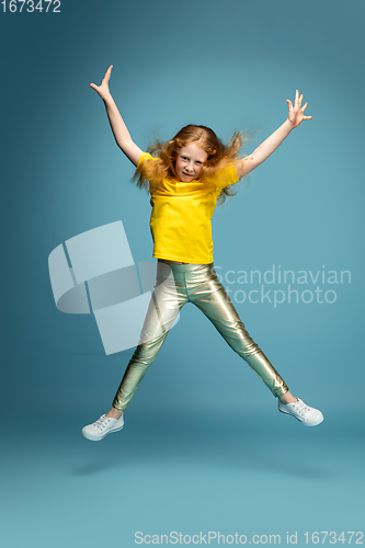 Image of Happy redhair girl isolated on blue studio background. Looks happy, cheerful, sincere. Copyspace. Childhood, education, emotions concept