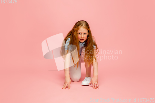 Image of Happy redhair girl isolated on pink studio background. Looks happy, cheerful, sincere. Copyspace. Childhood, education, emotions concept