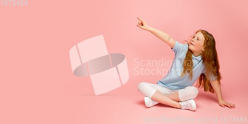 Image of Happy redhair girl isolated on pink studio background. Looks happy, cheerful, sincere. Copyspace. Childhood, education, emotions concept