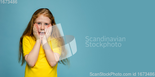 Image of Happy redhair girl isolated on blue studio background. Looks happy, cheerful, sincere. Copyspace. Childhood, education, emotions concept