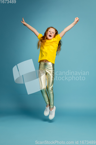 Image of Happy redhair girl isolated on blue studio background. Looks happy, cheerful, sincere. Copyspace. Childhood, education, emotions concept