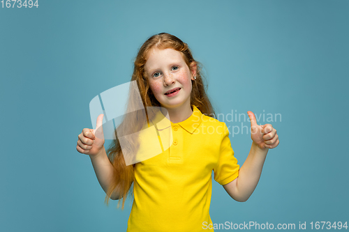 Image of Happy redhair girl isolated on blue studio background. Looks happy, cheerful, sincere. Copyspace. Childhood, education, emotions concept